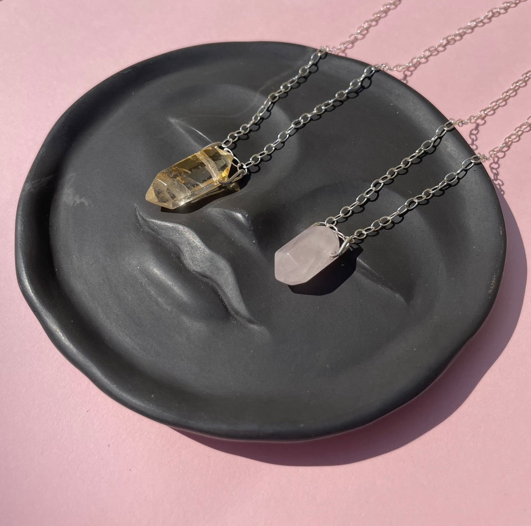 Citrine and rose quartz pendent necklaces on a moon face dish 