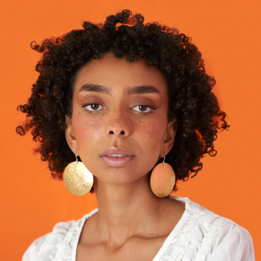 Model wearing supermoon earrings with orange background