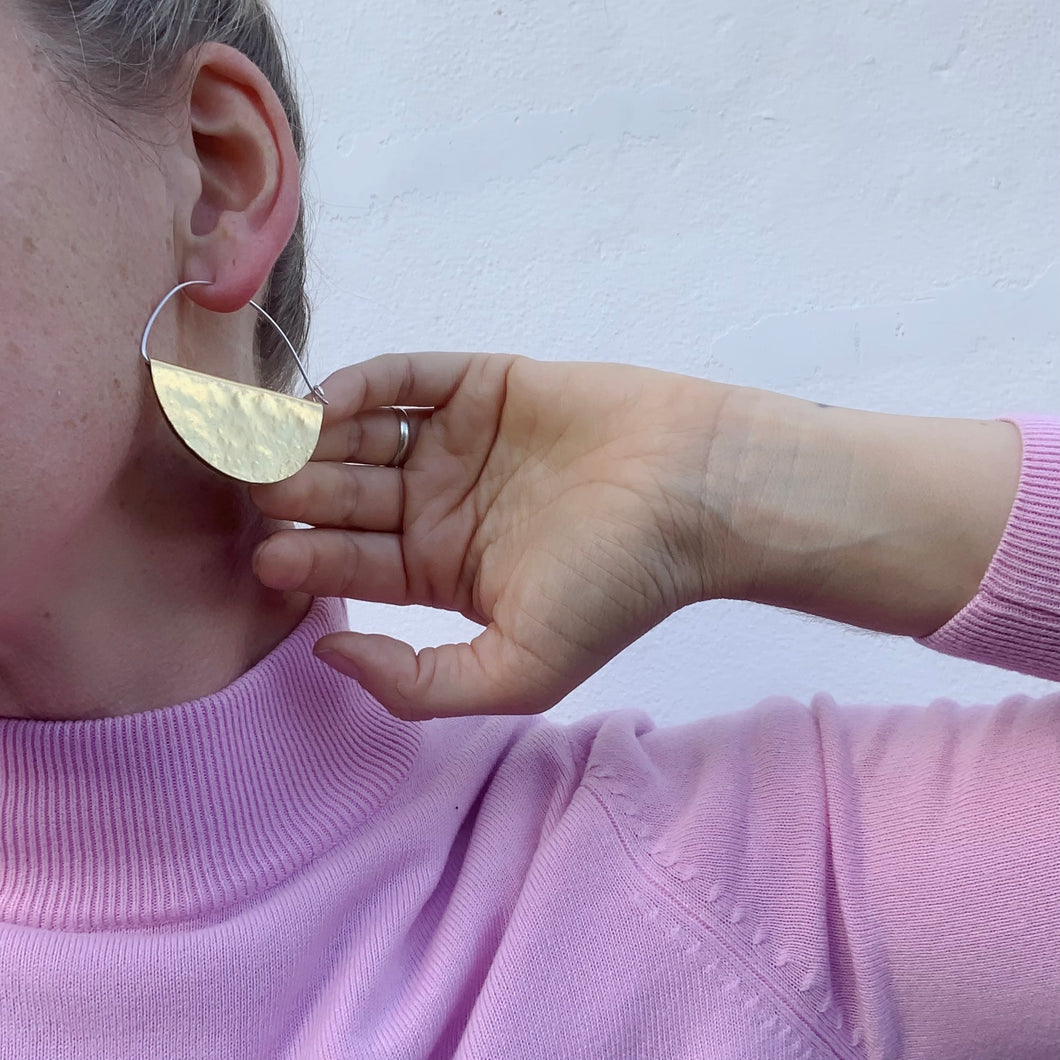 Brass and silver geometric cosmo hoops being worn 